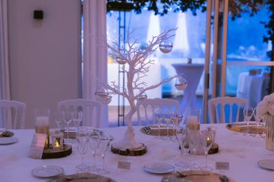 Salle de réception décorée avec des guirlandes lumineuses, des lanternes suspendues et des tables dressées pour un événement.