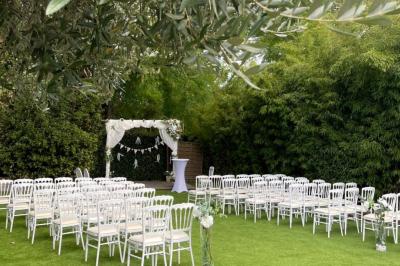 Salle de réception décorée avec des guirlandes lumineuses, des lanternes suspendues et des tables dressées pour un événement.
