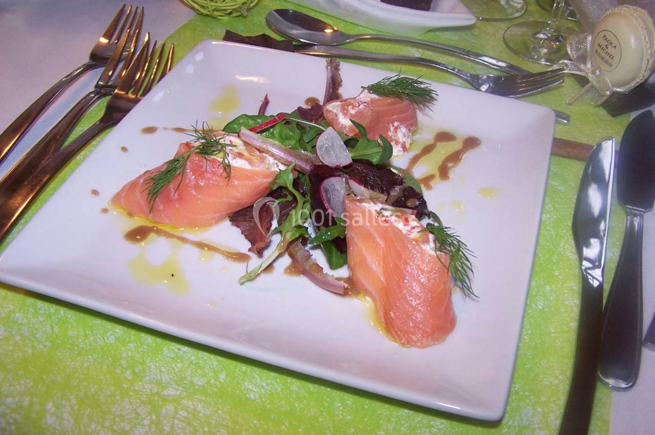 Assiette de saumon fumé accompagné de salade verte, radis et herbes fraîches, dressée avec une sauce.