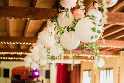 Salle de réception lumineuse avec des tables rondes dressées, nappes blanches et chaises rouges.