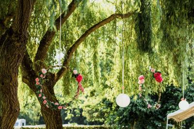 Salle de réception lumineuse avec des tables rondes dressées, nappes blanches et chaises rouges.