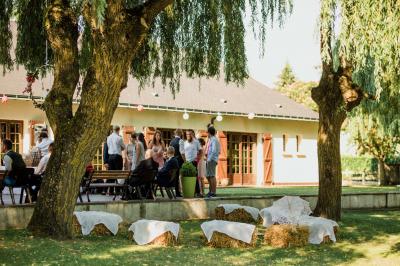 Salle de réception lumineuse avec des tables rondes dressées, nappes blanches et chaises rouges.