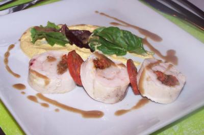 Salle de réception lumineuse avec des tables rondes dressées, nappes blanches et chaises rouges.