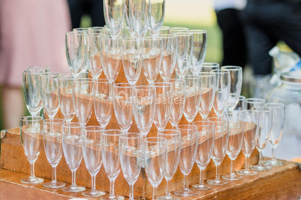 Pyramide de verres à pied transparents empilés sur des caisses en bois lors d'un événement en extérieur.