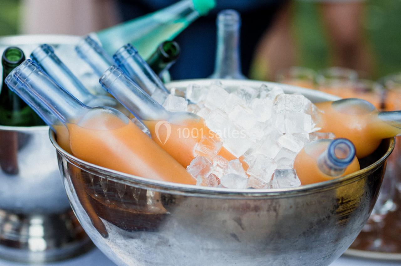 Bouteilles de jus orange disposées dans un saladier en métal rempli de glaçons.