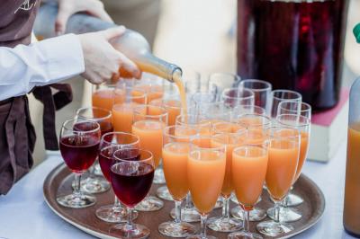 Salle de réception lumineuse avec des tables rondes dressées, nappes blanches et chaises rouges.