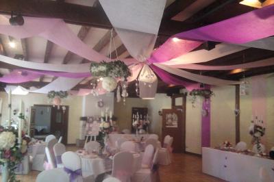 Salle de réception lumineuse avec des tables rondes dressées, nappes blanches et chaises rouges.