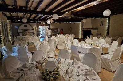Salle de réception lumineuse avec des tables rondes dressées, nappes blanches et chaises rouges.