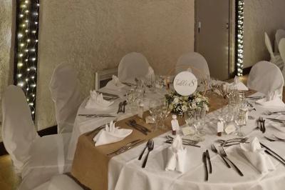 Salle de réception lumineuse avec des tables rondes dressées, nappes blanches et chaises rouges.
