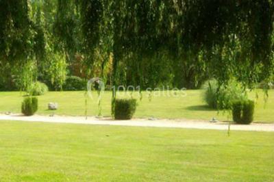 Salle de réception lumineuse avec des tables rondes dressées, nappes blanches et chaises rouges.