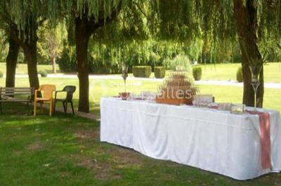 Salle de réception lumineuse avec des tables rondes dressées, nappes blanches et chaises rouges.
