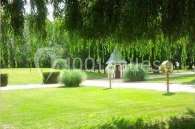 Salle de réception lumineuse avec des tables rondes dressées, nappes blanches et chaises rouges.