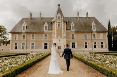 Façade d'un château avec une tour centrale et des fenêtres, entouré de végétation.