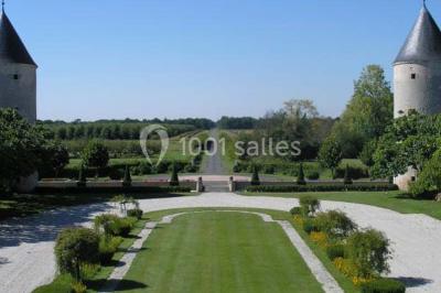 Façade d'un château avec une tour centrale et des fenêtres, entouré de végétation.