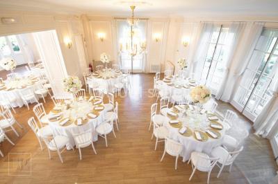 Allée bordée d'arbustes menant à une grande maison entourée d'arbres, capturée en noir et blanc.