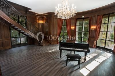 Allée bordée d'arbustes menant à une grande maison entourée d'arbres, capturée en noir et blanc.