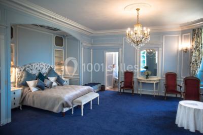 Allée bordée d'arbustes menant à une grande maison entourée d'arbres, capturée en noir et blanc.