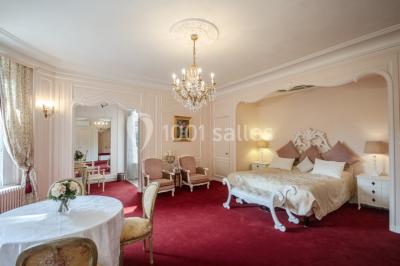 Allée bordée d'arbustes menant à une grande maison entourée d'arbres, capturée en noir et blanc.