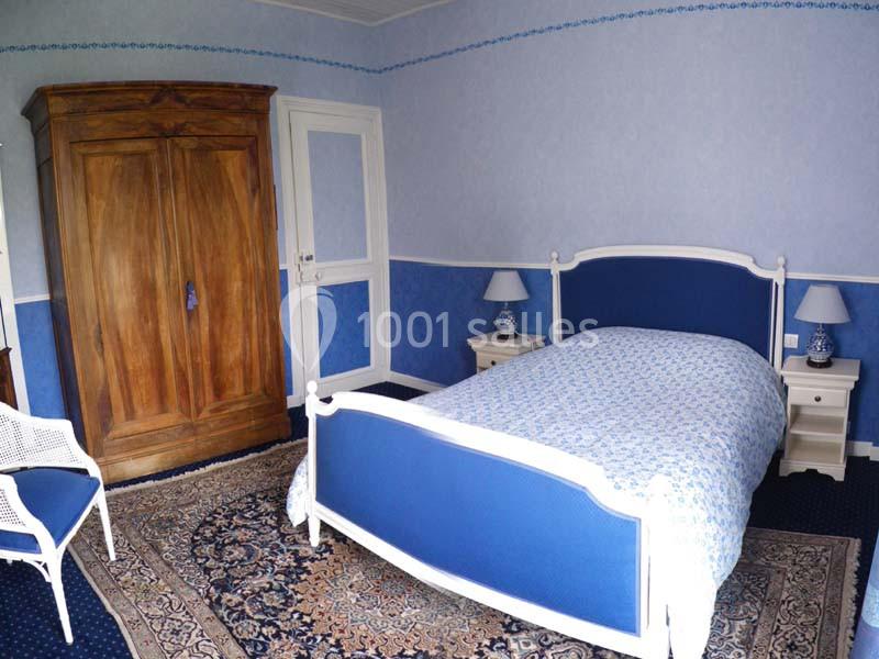 Chambre avec lit simple bleu, armoire en bois, tapis au sol et murs décorés de tons bleus.