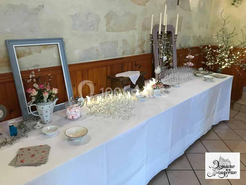 Table décorée pour un événement avec nappes blanches, verres, bougies, fleurs et éléments décoratifs.