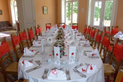 Miniature Location salle Saint-Paterne-Racan (Indre-et-Loire) - Domaine de la Fougeraie #15 Table dressée pour un repas festif dans une salle lumineuse, avec chaises décorées de nœuds rouges et vaisselle élégante.