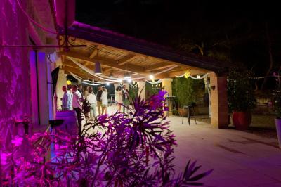 Cour extérieure ensoleillée avec des plantes en pots, des chaises en métal et un bâtiment à toit de tuiles en arrière-plan.