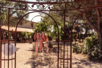 Cour extérieure ensoleillée avec des plantes en pots, des chaises en métal et un bâtiment à toit de tuiles en arrière-plan.
