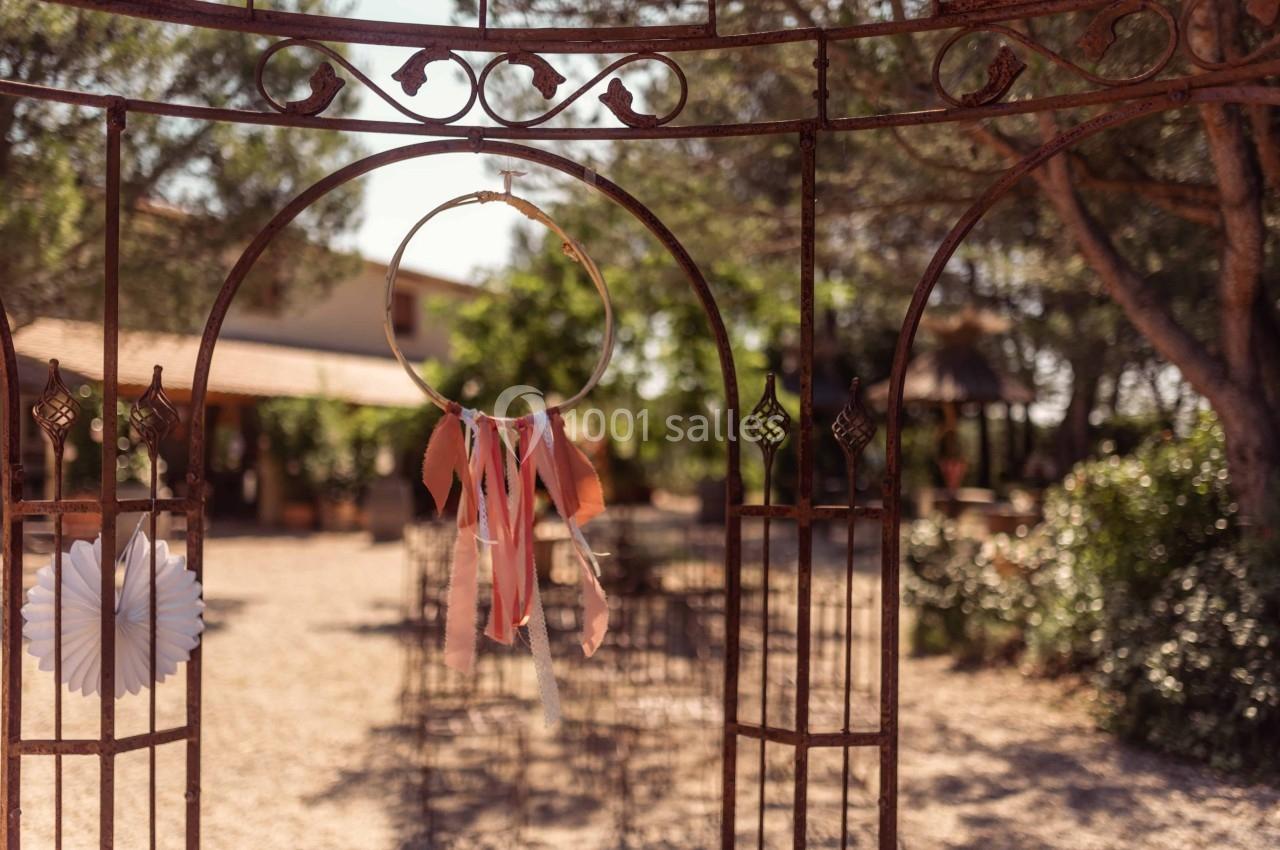 Attrait métallique décoré avec un attrape-rêves coloré, donnant sur un jardin ensoleillé avec des chaises disposées.