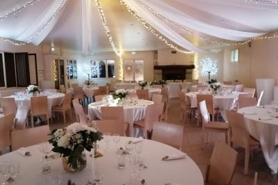 Cour extérieure ensoleillée avec des plantes en pots, des chaises en métal et un bâtiment à toit de tuiles en arrière-plan.