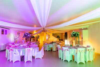 Cour extérieure ensoleillée avec des plantes en pots, des chaises en métal et un bâtiment à toit de tuiles en arrière-plan.