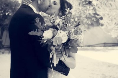 Cour extérieure ensoleillée avec des plantes en pots, des chaises en métal et un bâtiment à toit de tuiles en arrière-plan.