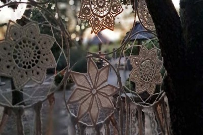 Cour extérieure ensoleillée avec des plantes en pots, des chaises en métal et un bâtiment à toit de tuiles en arrière-plan.