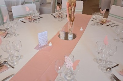 Cour extérieure ensoleillée avec des plantes en pots, des chaises en métal et un bâtiment à toit de tuiles en arrière-plan.