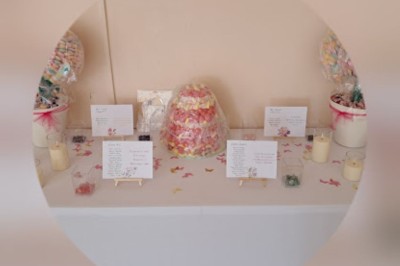 Cour extérieure ensoleillée avec des plantes en pots, des chaises en métal et un bâtiment à toit de tuiles en arrière-plan.