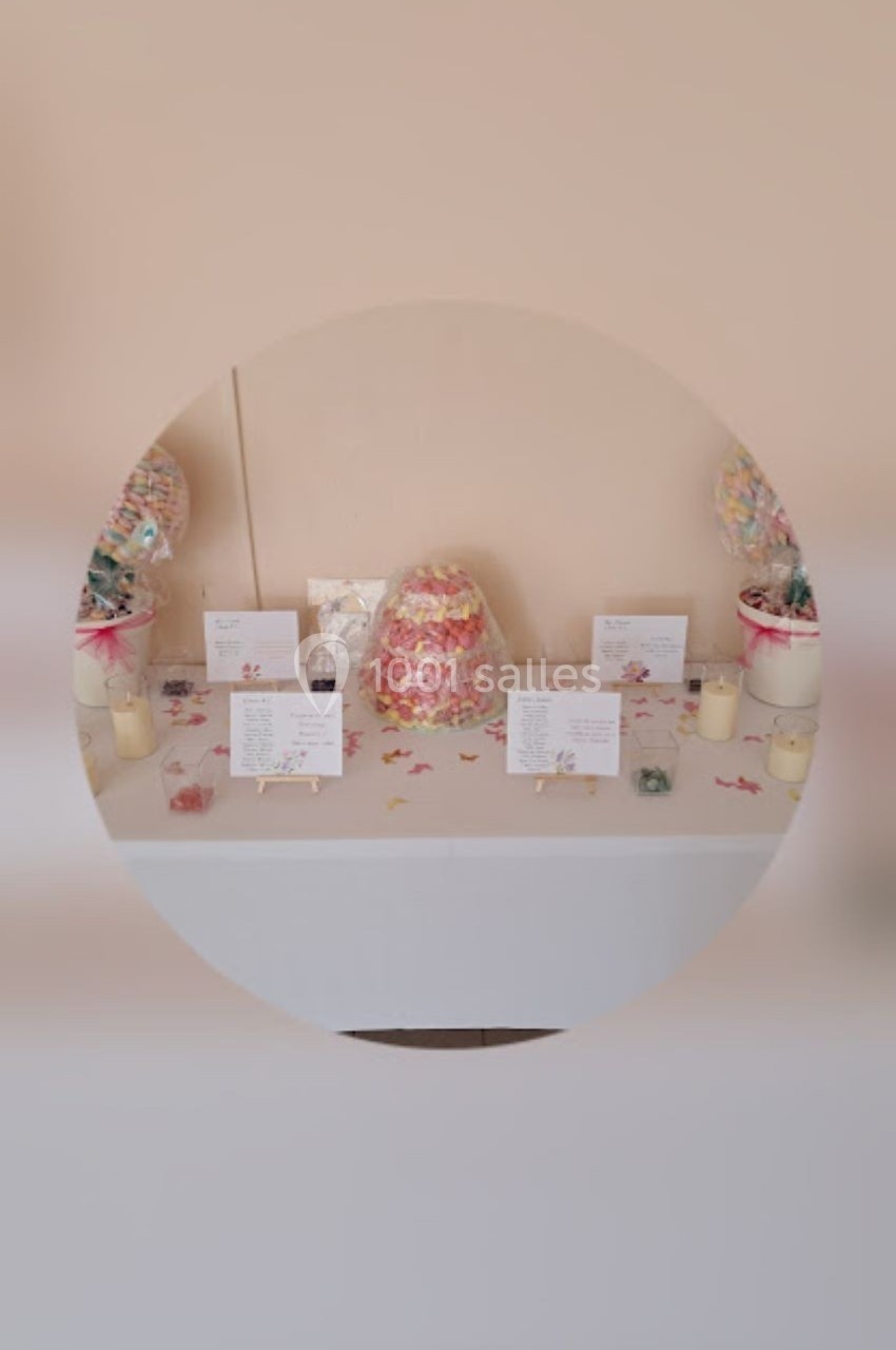 Table décorée avec des bonbonnières, des cartes et des bougies, sur fond beige.