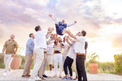 Cour extérieure ensoleillée avec des plantes en pots, des chaises en métal et un bâtiment à toit de tuiles en arrière-plan.