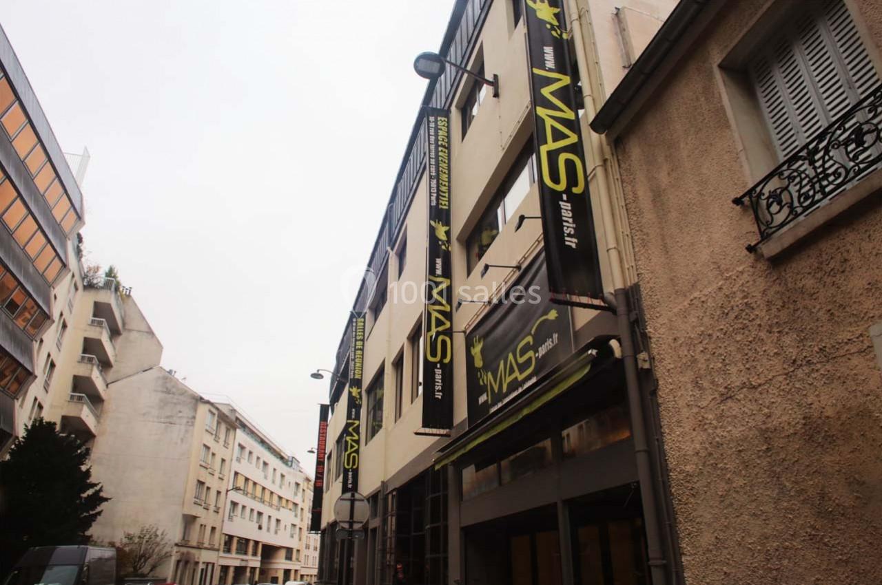 Façade d'un bâtiment avec des enseignes ’MAS’ visibles, situé dans une rue bordée d'immeubles.