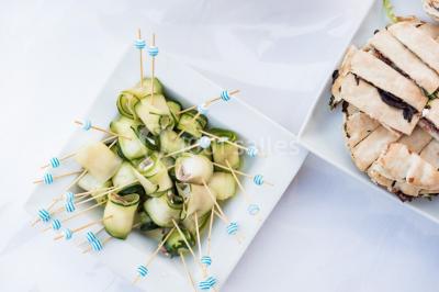 Assortiment de tartinades dans des bols blancs posés sur une rondelle de bois, avec des amuse-bouches en arrière-plan.