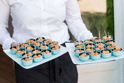 Assortiment de tartinades dans des bols blancs posés sur une rondelle de bois, avec des amuse-bouches en arrière-plan.