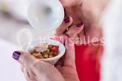 Assortiment de tartinades dans des bols blancs posés sur une rondelle de bois, avec des amuse-bouches en arrière-plan.