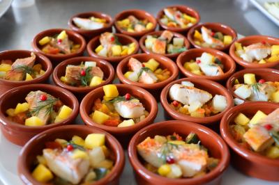 Assortiment de tartinades dans des bols blancs posés sur une rondelle de bois, avec des amuse-bouches en arrière-plan.