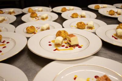 Assortiment de tartinades dans des bols blancs posés sur une rondelle de bois, avec des amuse-bouches en arrière-plan.