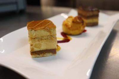 Assortiment de tartinades dans des bols blancs posés sur une rondelle de bois, avec des amuse-bouches en arrière-plan.