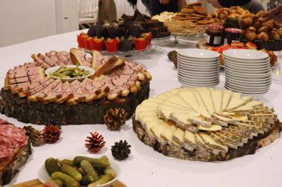 Assortiment de tartinades dans des bols blancs posés sur une rondelle de bois, avec des amuse-bouches en arrière-plan.