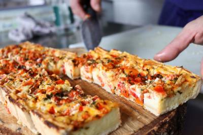 Assortiment de tartinades dans des bols blancs posés sur une rondelle de bois, avec des amuse-bouches en arrière-plan.