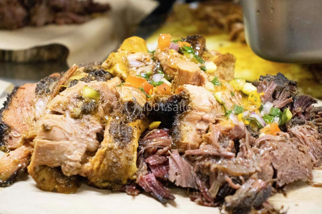 Viande effilochée garnie de légumes colorés et d'une sauce, servie sur une planche en bois.
