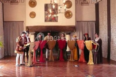 Un groupe de personnes en costumes d'époque chante autour de lutrins dans une salle décorée de style ancien.
