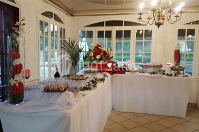 Buffet élégant avec verrines colorées, petits plats variés et décoration florale blanche sur nappes blanches.