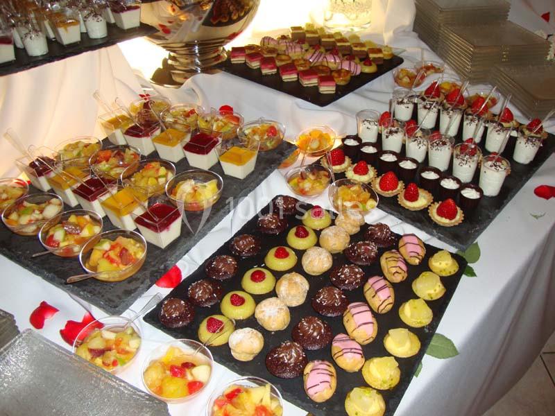 Buffet de desserts variés comprenant verrines, pâtisseries et fruits, disposés sur des plateaux noirs.