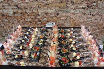 Buffet élégant avec verrines colorées, petits plats variés et décoration florale blanche sur nappes blanches.